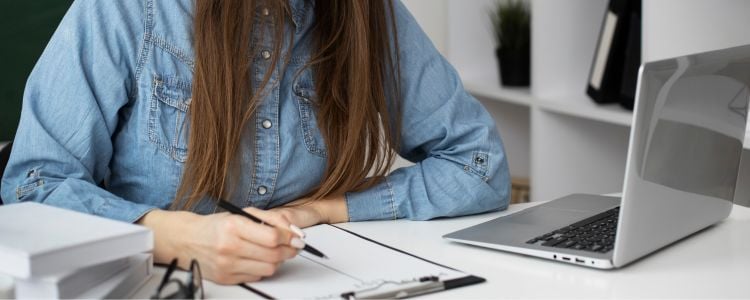mujer estudiando con una laptop y libreta enfrentando los desafíos de la educación universitaria