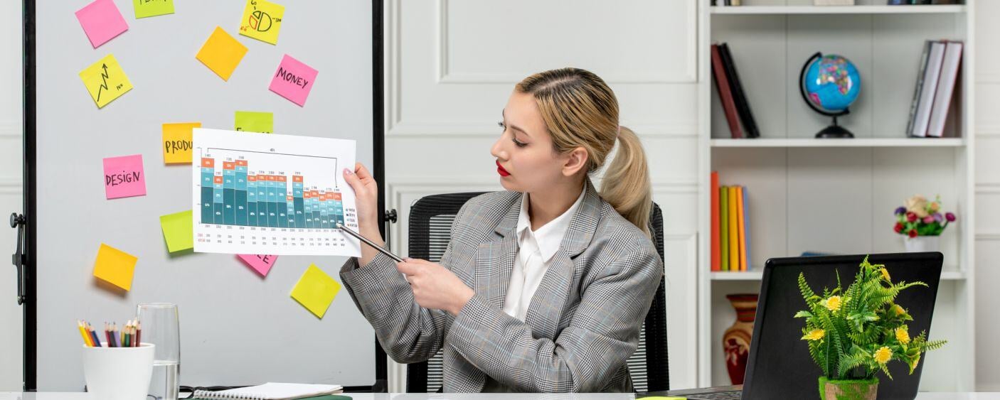 Mujer señalando gráfico enfrente de pizarrón aplicando la mercadotecnia