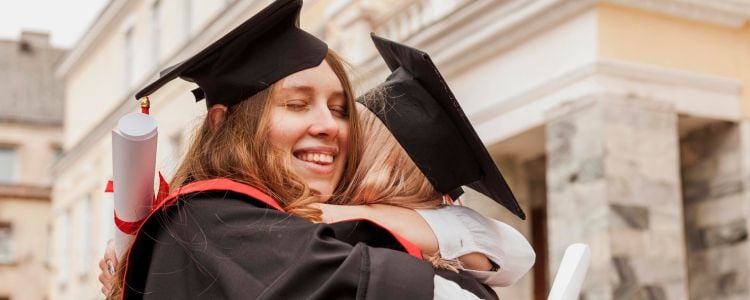 Mujeres graduadas abrazándose tras revolucionar su aprendizaje