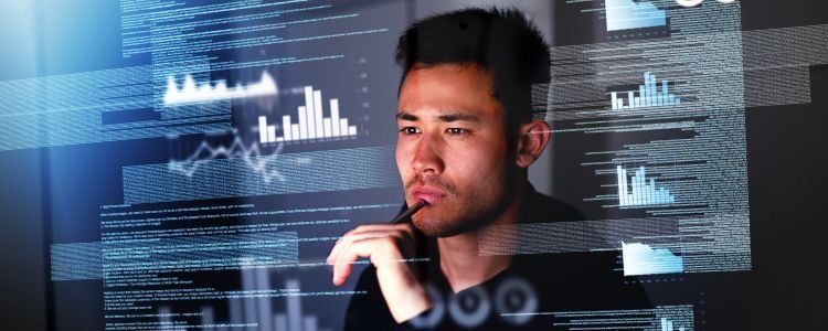 Hombre joven revisa una serie de datos en una pantalla mientras adquiere un gesto reflexivo
